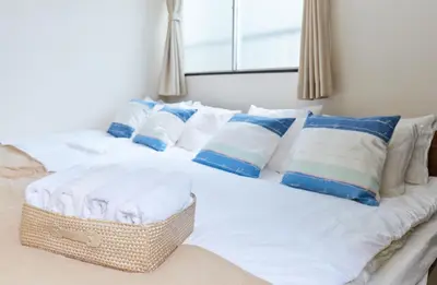 a white bed with blue and white pillows at H-Nishikamata ColorBee House in Tokyo