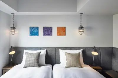 two beds in a bedroom with two lamps at Hotel Resol Akihabara in Tokyo
