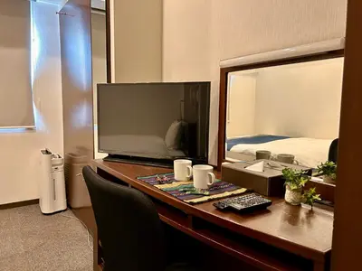 a bedroom with a desk with a television and a bed at Cypressinn Tokyo in Tokyo