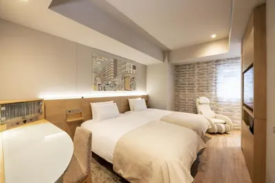 a hotel room with two beds and a chair at remm Tokyo Kyobashi in Tokyo