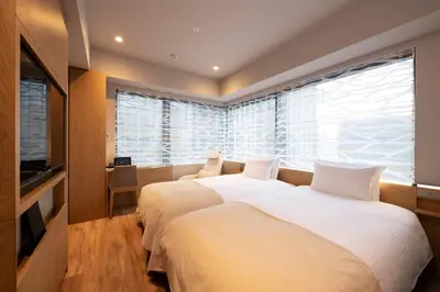 two beds in a room with a large window at remm Tokyo Kyobashi in Tokyo