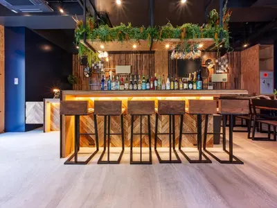 a bar with wooden stools and plants on the wall at Focus Kuramae in Tokyo