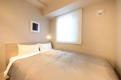 a bedroom with a large white bed with a window at S-peria Inn Nihombashi Hakozaki in Tokyo