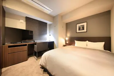 a bedroom with a bed and a desk and a television at S-peria Inn Nihombashi Hakozaki in Tokyo