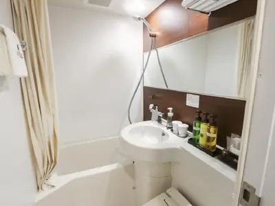 a bathroom with a sink and a toilet and a mirror at HOTEL LiVEMAX Akihabara Kita in Tokyo