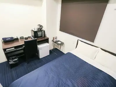 a hotel room with a bed and a desk with a computer at HOTEL LiVEMAX Akihabara Kita in Tokyo