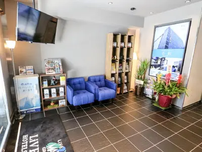 a waiting room with blue chairs and a flat screen tv at HOTEL LiVEMAX Akihabara Kita in Tokyo
