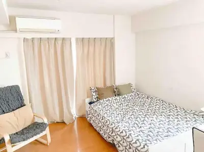 a white bedroom with a bed and a chair at Urban Core Shikano 501 in Tokyo