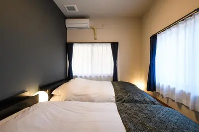 a bedroom with a bed with white sheets and a window at Ryokan Ichinao in Tokyo