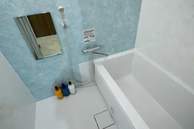a bathroom with a white tub and a shower with a mirror at Ryokan Ichinao in Tokyo