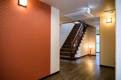 a hallway with a staircase and orange wall at Ryokan Ichinao in Tokyo