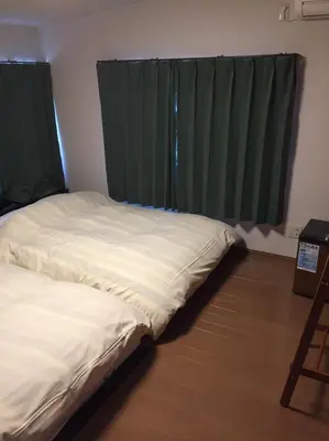a bed in a room with green curtains at Ryokan Ichinao in Tokyo