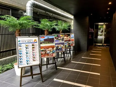 a row of signs in front of a building with palm trees at HOTEL LiVEMAX Kasai Ekimae in Tokyo