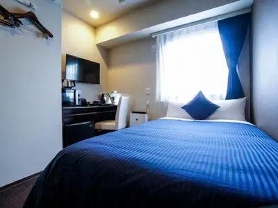 a bedroom with a blue and white bed with a window at HOTEL LiVEMAX Kasai Ekimae in Tokyo