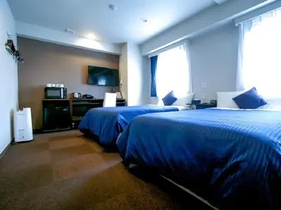 two beds in a hotel room with blue sheets at HOTEL LiVEMAX Kasai Ekimae in Tokyo