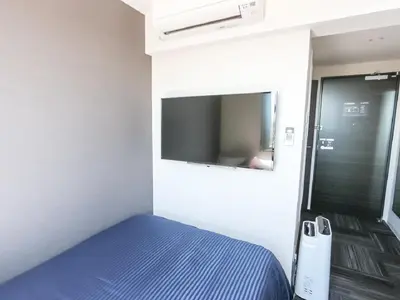 a small bedroom with a blue bed and a mirror at HOTEL LiVEMAX Takadanobaba Ekimae in Tokyo