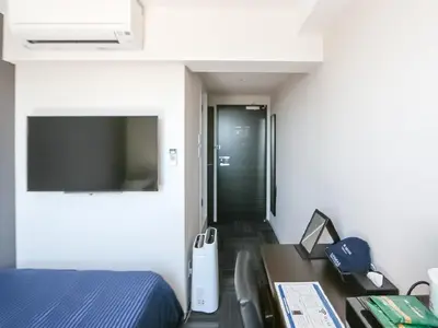 a bedroom with a bed and a desk and a television at HOTEL LiVEMAX Takadanobaba Ekimae in Tokyo