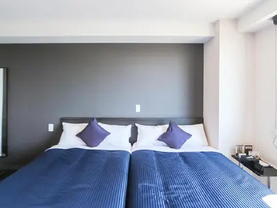 two beds with blue and white pillows in a bedroom at HOTEL LiVEMAX Takadanobaba Ekimae in Tokyo