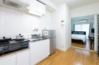 a kitchen with a sink and a stove and a bedroom at Evergreen hotel ichigaya luxe in Tokyo