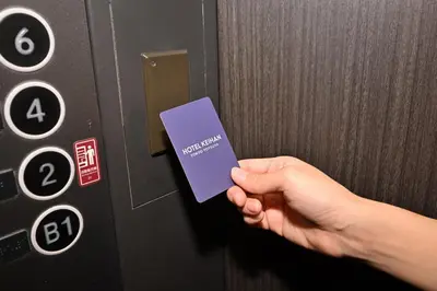 a person is holding a purple card in an elevator at Hotel Keihan Tokyo Yotsuya in Tokyo
