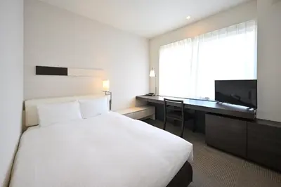 a bedroom with a bed and a desk and a television at Hotel Keihan Tokyo Yotsuya in Tokyo