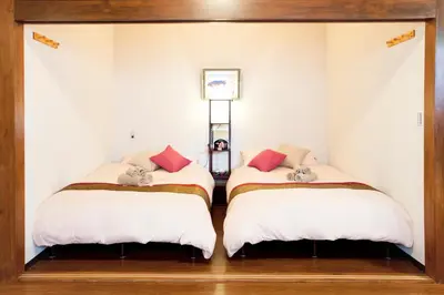 two beds in a room with white walls at Nagomi House in Tokyo