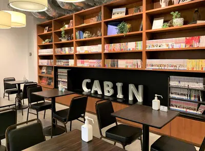 a library with tables and chairs and bookshelves at First Cabin Ichigaya in Tokyo