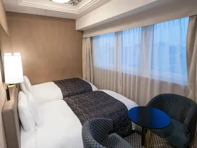 a hotel room with a bed and chairs and a window at APA Hotel Nihombashi Bakurocho Ekimae in Tokyo