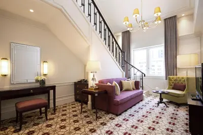 a living room with a purple couch and a piano at The Tokyo Station Hotel in Tokyo