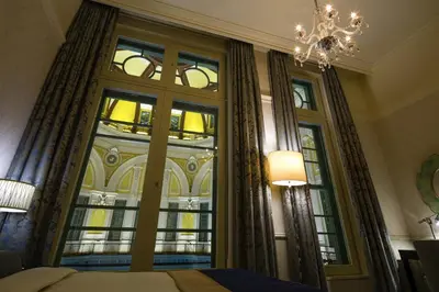a bedroom with a large window and a chandelier at The Tokyo Station Hotel in Tokyo