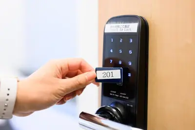 a person holding a remote control with a number on it at Oku Apartment in Tokyo