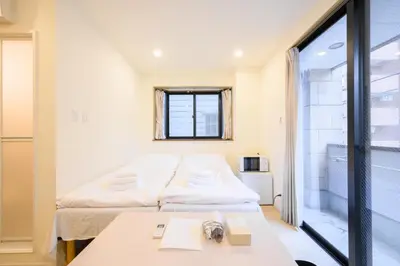 a small room with two beds and a table at Oku Apartment in Tokyo