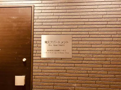 a sign is posted on a brick wall at Oku Apartment in Tokyo