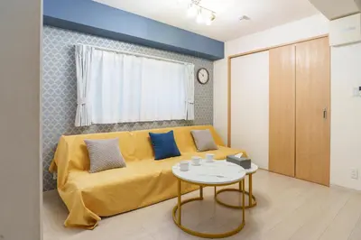 a living room with a yellow couch and a table at The Emilio 102 Shinjuku Near Shibuya in Tokyo