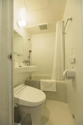 a white bathroom with a toilet and a sink at DOMO Hotel in Tokyo