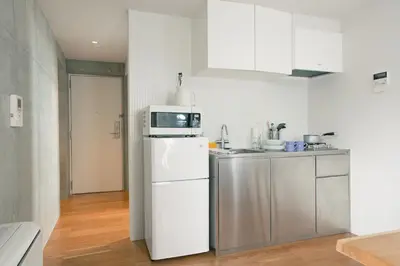 a white kitchen with a microwave on top of a refrigerator at DOMO Hotel in Tokyo