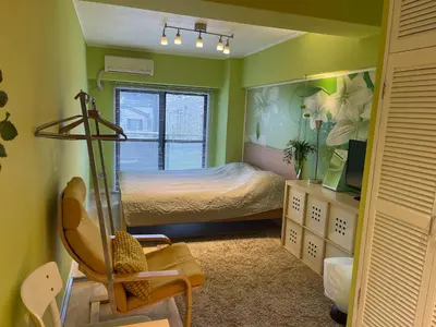 a bedroom with a bed and a chair and a window at only 2 stops to shibuya sangenjaya apt in Tokyo