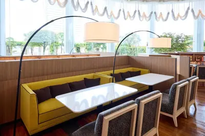a restaurant with a yellow couch and tables and chairs at ANA Holiday Inn Tokyo Bay by IHG in Tokyo