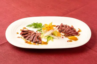 a plate of food with meat on a red table at Pearl Hotel Shinjuku Akebonobashi in Tokyo