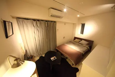 a small bedroom with a bed and a lamp at Sorapia Tokyo in Tokyo
