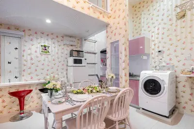 a kitchen with a table with chairs and a washing machine at Papillon Paradis Nishi-Shinjuku in Tokyo