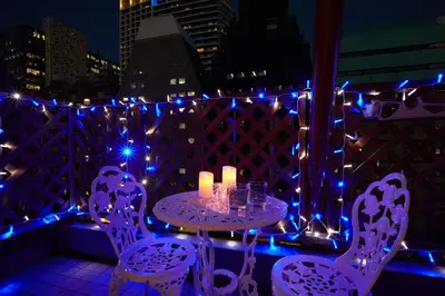 a table and chairs on a balcony with lights at Papillon Paradis Higashi-Shinjuku in Tokyo