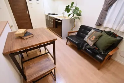 a living room with a black leather couch and a table at Origami Residential Suite - Tokyo Asakusa Skytree in Tokyo
