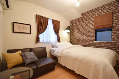 a bedroom with a bed and a couch and a brick wall at Origami Residential Suite - Tokyo Asakusa Skytree in Tokyo