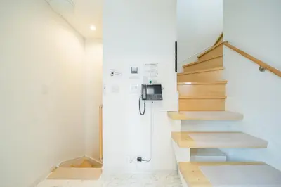 a staircase in a home with white walls and wooden stairs at QiQi House Tokyo まるごと新築一軒家宿 Spacious New Home, 8 Guests, Easy Airport & Disney Access in Tokyo
