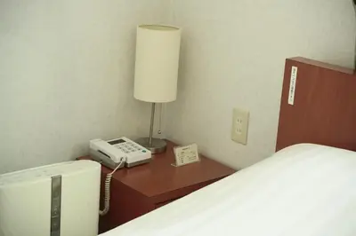 a bedroom with a bed and a phone and a lamp at Hotel New Takada in Tokyo