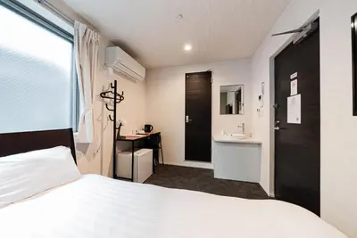 a bedroom with a white bed and a sink at GLOU Higashi Shinjuku in Tokyo