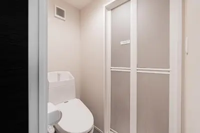a white bathroom with a toilet and a shower at GLOU Higashi Shinjuku in Tokyo