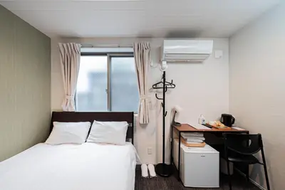 a bedroom with a bed and a desk and a window at GLOU Higashi Shinjuku in Tokyo