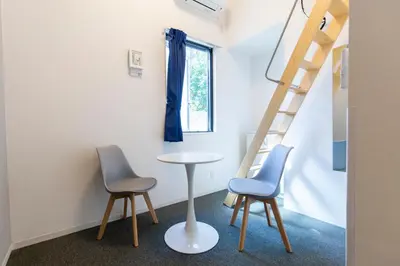 a room with two chairs and a table and a ladder at GLOU Higashi Shinjuku in Tokyo